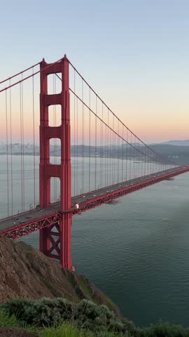 Golden Gate Bridge at sunset over the water with city skyline in the background, San Francisco, California