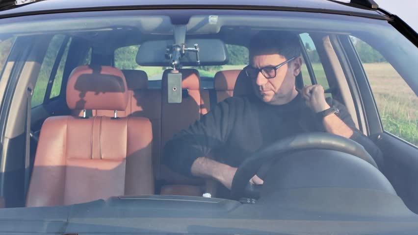 Safe-drive concept: Front view of a driver getting into a car and putting on a seat belt