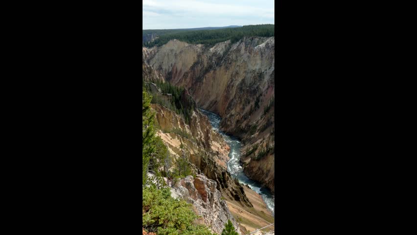 Beautiful vertical clip of the colorful Yellowstone canyon with the Yellowstone River flowing through the canyon. Notice the yellow-colored minerals in the rocks that gives the canyon its name. 
