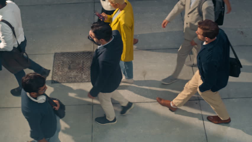 Lively Mix of Pedestrians From Different Backgrounds Walk on a City Street, Reflecting the Energy of the Urban Environment. Young Male and Female Navigate the Crowded Sidewalk. High Angle Footage
