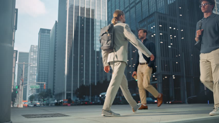Diverse Group of Young Professionals Walking on a Busy Street, Some Engaged in Conversation, Others Focused on Their Devices, Capturing the Essence of Urban Hustle and Dynamic City Life. Side View