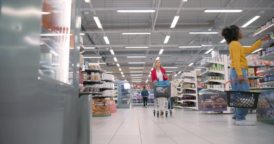 Group of Diverse Shoppers, Including Parents With Children, Casually Walks Through the Grocery Store, Selecting Food Items for the Week. Shop is Packed With Cans, Coffee, Produce and Packaged Goods