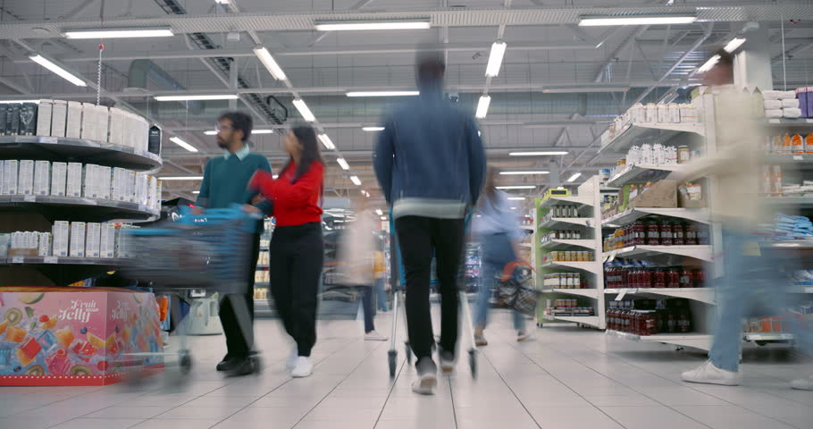 Diverse Male and Female Shoppers, Including Families and Individuals with Shopping Carts and Baskets, Navigate Supermarket Aisles. People Shopping for Groceries. Establishing Timelapse Footage