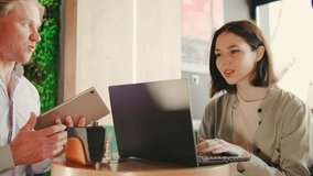 Brunette woman works on her laptop at a coffee shop table while a waiter approaches with a tablet to take her order - Powered by Shutterstock - Get 15% off with code: PIKWIZARD15
