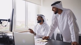 Cinematic video of two businessmen working together in a modern office in the united arab emirates. Business people with the traditional white kandura in Dubai. - Powered by Shutterstock - Get 15% off with code: PIKWIZARD15
