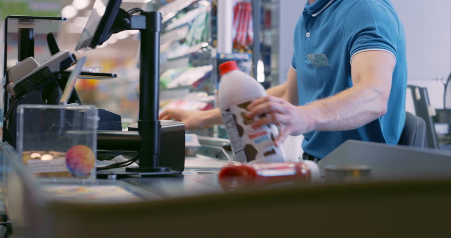 Male Cashier Scanning Product Items for Diverse Customers at a Busy Supermarket Checkout. Meat, Bananas, Eggs, Milk are Processed Efficiently, Groceries Rolling Down the Conveyor Belt