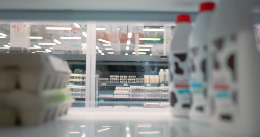 Beautiful Young African American Woman in a Yellow Sweater Takes a Milk Bottle and a Pack of Eggs From a Supermarket Fridge. POV Portrait of a Grocery Shopper From Inside the Fridge