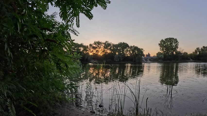 sunset on the river. sunrise on the lake shore. sun behind the trees. beautiful natural landscape with sunset and water. high definition video. sun glare on water. dark water in the river.
