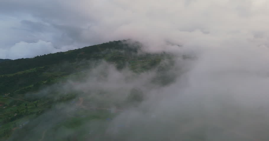 Drone shot capturing Nepali village in Dolakha clouds over rolling hills in both sunny and gloomy weather. The scene shows uniquely amazing greenery and serene beauty of landscape.