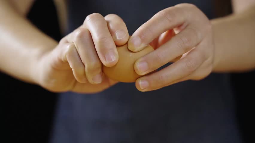 closeup of breaking eggs with women