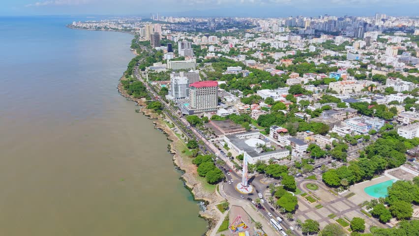 Aerial wide shot of Santo Domingo City with coastal road at sunny day. Panorama high angle view over town with downtown in background. Capital of Dominican Republic in Summer. Caribbean Sea view.