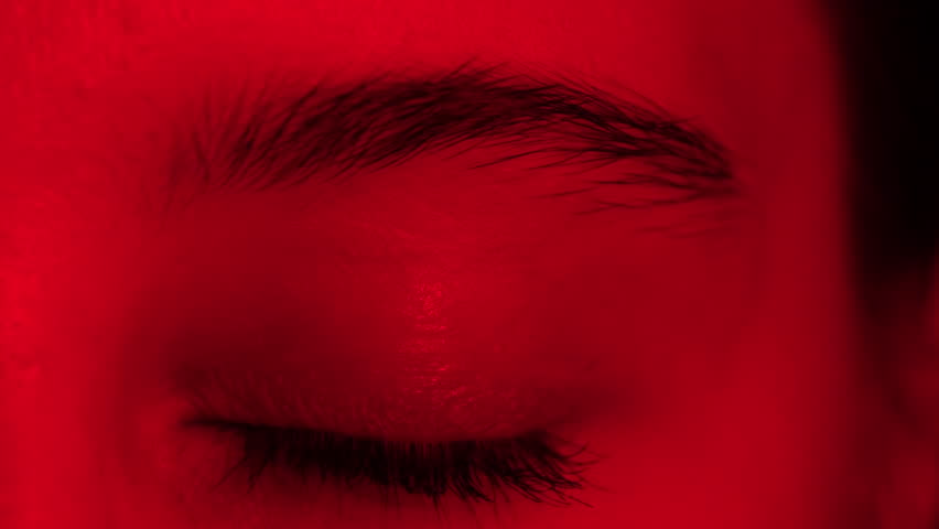 Close-Up View Of A Girl'S Large Eye Blinking In Red Light