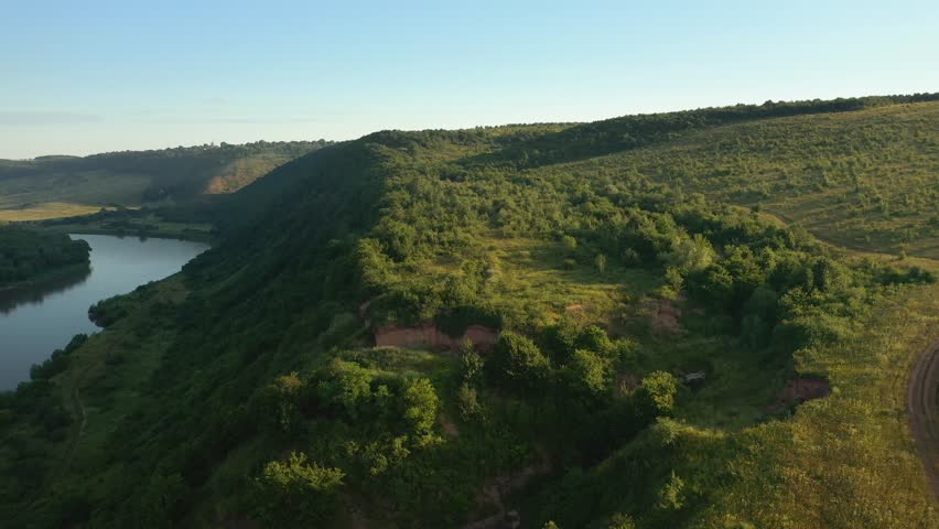 Aerial footage of a majestic river flowing through a hilly area. Location place Dniester Canyon, Ukraine, Europe. Cinematic drone shot. Filmed in UHD 4k video. Discover the beauty of earth.
