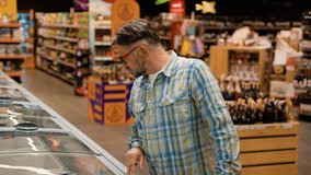 Middle-aged man takes fresh red fish salmon from refrigerator in a supermarket - Powered by Shutterstock - Get 15% off with code: PIKWIZARD15