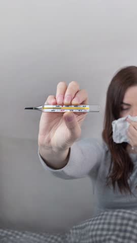 Woman caught a cold, got sick, she shows mercury thermometer with a temperature of 38 C. vertical