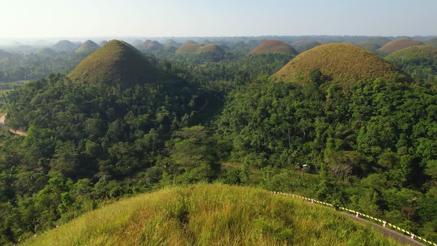 4K drone video flying over the Chocolate Hills in Bohol, Philippines. These hills are green during the rainy season, but turn brown during the dry season. They are a very popular tourist destination.