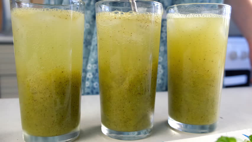 Mixing sparkling water with green kiwi puree preparing lemonade in glasses on kitchen at home. Recipe cuisine professional culinary. Prepare delicious fruit dessert homemade beverage drink.