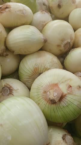 Close-up of a heap of fresh onions on a market shelf.