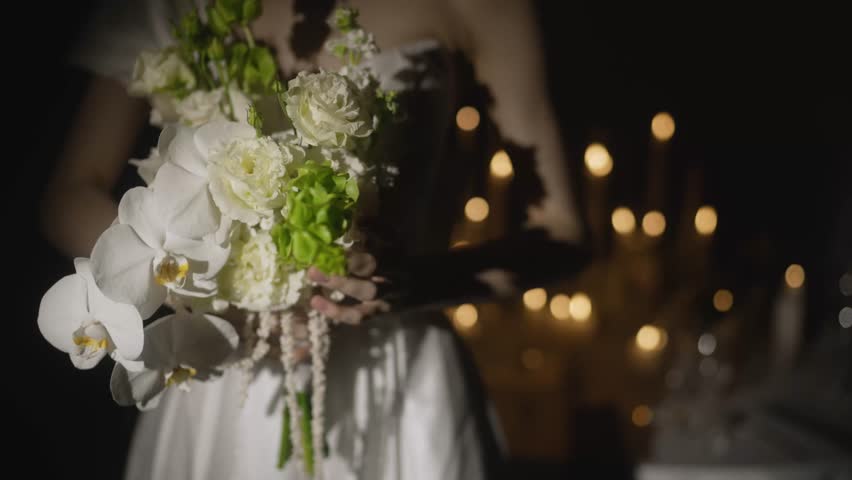 Bride holding wedding bouquet with orchids posing in restaurant.
