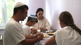 jewish family celebrating hanukkah, israel, boy in kippah, jewish holidays, yom kippur feast, table with food, honey, donuts, family holiday, religious family, family praying, food on the table - Powered by Shutterstock - Get 15% off with code: PIKWIZARD15