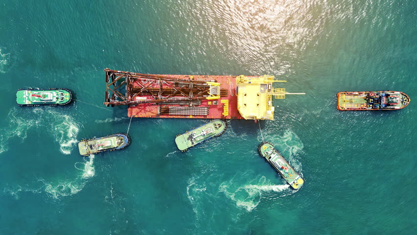 Big Construction on ship. Tender Drilling Oil Rig on Barge Ship transportation Rid to Oil Rig in The Middle of The Ocean. Five Tug boat pulling Construction 	