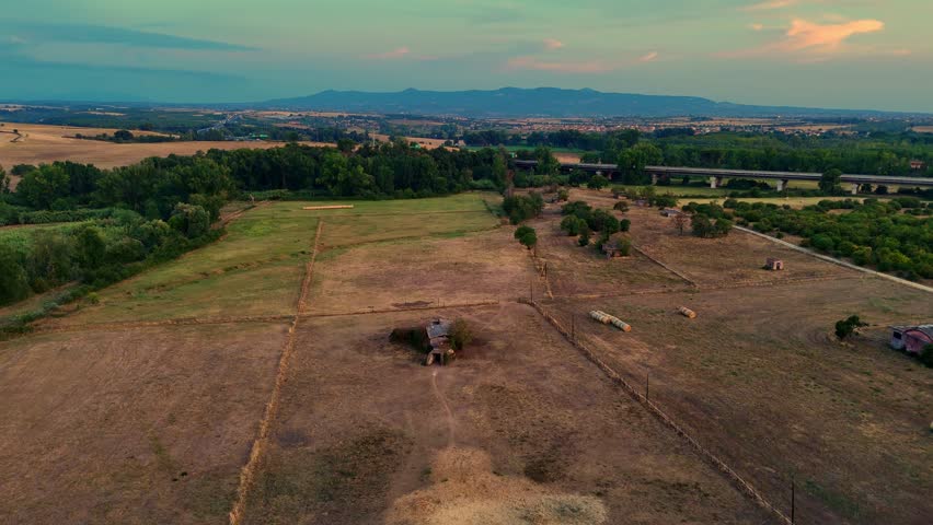 Camera panning over abandoned farm with highway in background