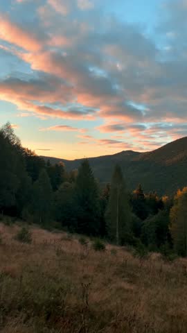 landscape sunrise, forest and mountains in the clouds, autumn colors, pink and red, soft dawn light, golden hour, beauty of nature, poster, postcard, screensaver, Carpathians