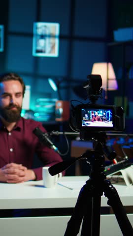 Vertical video Content creator hosting online show in rgb lights studio, shooting vlog using professional gear. Vlogger presenting informations during streaming service broadcast filmed with camera