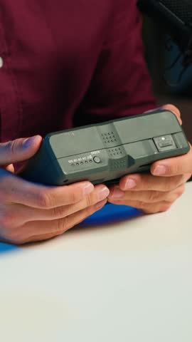 Vertical video Tech content creator filming technology review of V mount battery, unpacking it and presenting specifications to audience, close up. Influencer showing charging device to subscribers