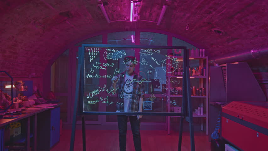 Young man solves equations in laboratory. Media. Student solves mathematical equations in secret classroom. Laboratory for experiments with mathematical calculations on blackboard - Powered by Shutterstock - Get 15% off with code: PIKWIZARD15