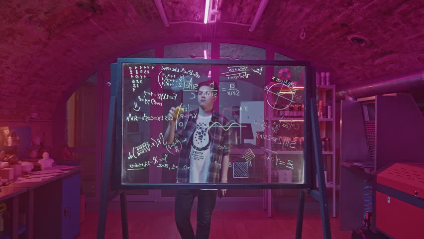 Man solves equations on transparent board. Media. Young man solves equations in closed laboratory. Man solves mathematical equations on blackboard with marker - Powered by Shutterstock - Get 15% off with code: PIKWIZARD15