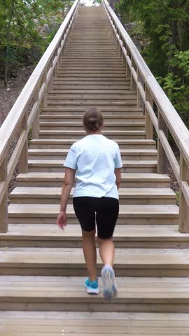 Athletic young woman walking up a Fitness Stairs in a natural park in the woods in Finland.