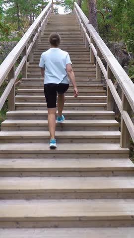 Athletic young woman walking up a Fitness Stairs in a natural park in the woods in Finland.