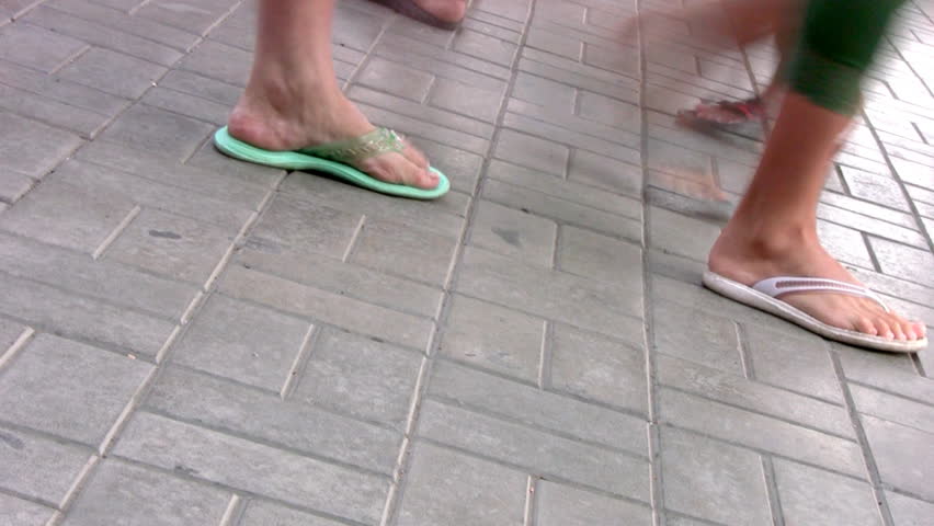 Summer. Different people are on a pedestrian street. We can see only his legs.