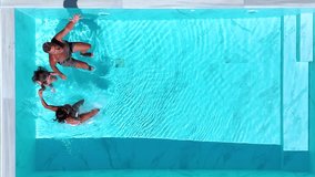 Aerial top view of a happy family jumping together in the pool as a summer travel concept with copy space - Powered by Shutterstock - Get 15% off with code: PIKWIZARD15