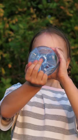 Girl, boy children kids drink water after active games in nature outside. Children replenish thirst, water balance in body, get rid of dehydration. Children kids greedily drink water from bottle.