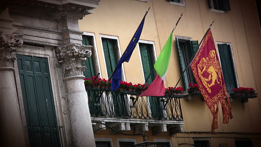 Building in Venice. On the balcony hanging flags: - city of Venice, - country of