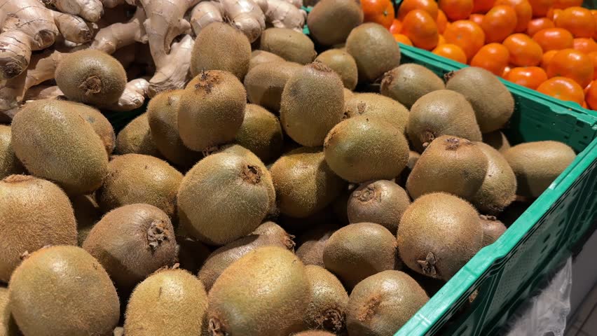 Female hand choosing fresh kiwi in supermarket. High quality 4k footage.