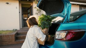 A woman in a white shirt carries groceries from her car to her house. Rear view of young woman approaches her front door, balancing multiple grocery bags filled with fresh produce and a baguette - Powered by Shutterstock - Get 15% off with code: PIKWIZARD15