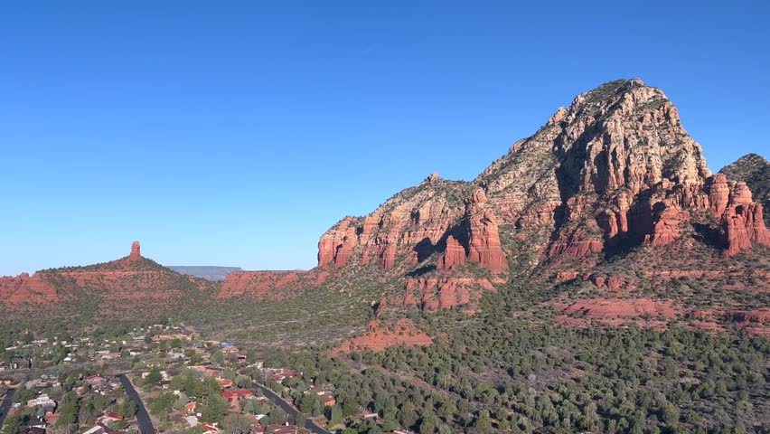 Scenic aerial view of the red rocks of Sedona, Arizona with a view from Sugarloaf Mountain. This beautiful landscape features lush green trees, red rock formations, and a residential area below - USA