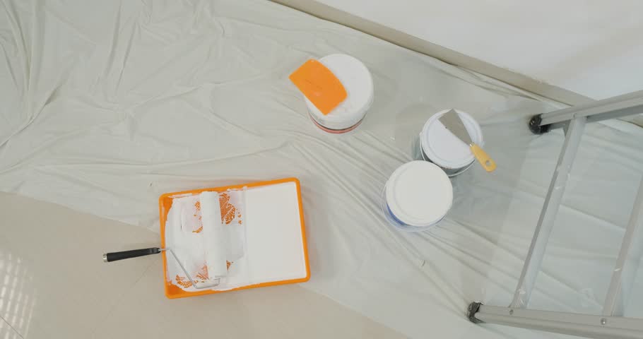 Top view of repair tools stepladder, paint cans, brushes, and roller. Concept of renovation in a new apartment before moving. Painters. Background for renovation work.