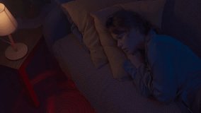 Woman in pajama sleeping in bed in dark apartment room, monster hiding under bed. Girl waking up, red light under sofa. Halloween horror concept. - Powered by Shutterstock - Get 15% off with code: PIKWIZARD15