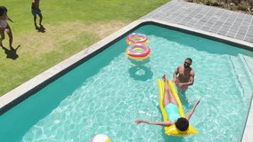 Happy african american son and daughter jumping into swimming pool to parents. Summer, family, fun, togetherness, vacations, free time, relaxation and lifestyle, unaltered. - Powered by Shutterstock - Get 15% off with code: PIKWIZARD15