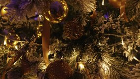 Christmas tree decorated with golden baubles, illuminated by warm lights, creating a festive atmosphere. 4K video - Powered by Shutterstock - Get 15% off with code: PIKWIZARD15