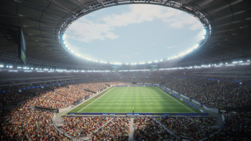 Day Drone Flight Around American Football Stadium. Aerial View over Massive Crowd of Fans. Arena Hosts Major Sport Event With Thousands of Spectators. 360 Degree Orbital Cinematic Shot