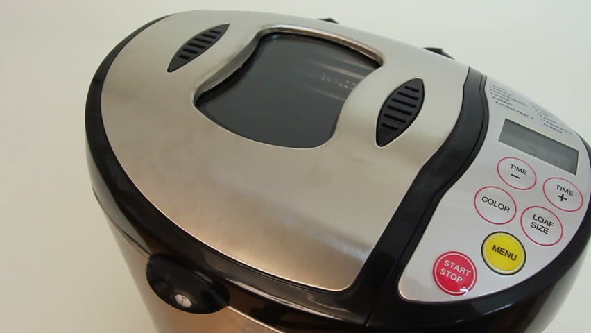 Hand presses buttons on bread machine's panel for baking
