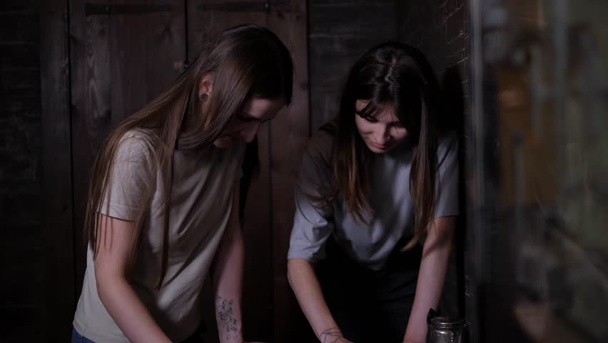 Close-up of young people spinning discs on a wooden board in a dark quest room, a logical task for passing tests. Hands on a spiritualistic wooden board in a dark creepy room.
