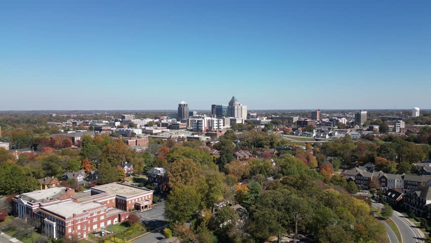 A drone footage of autumn trees and the skyline of Greensboro city on a sunny day in North Carolina
