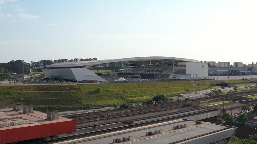 Aerial view of Arena Corinthians stadium in São Paulo, Brazil, with train tracks and a train passing by.