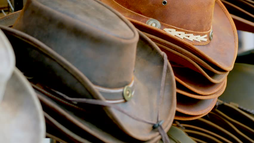 A closeup shot of the leather cowboy hats displaying for sale outside a retail shop in daytime with blur background